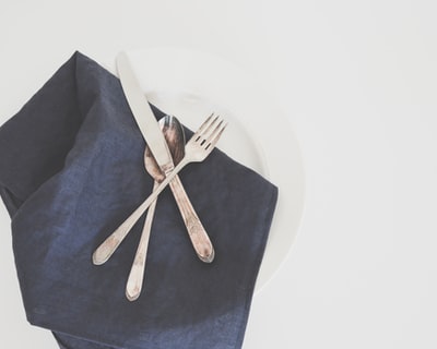 灰色的叉子,勺子,和黄油刀板与黑色的餐巾
